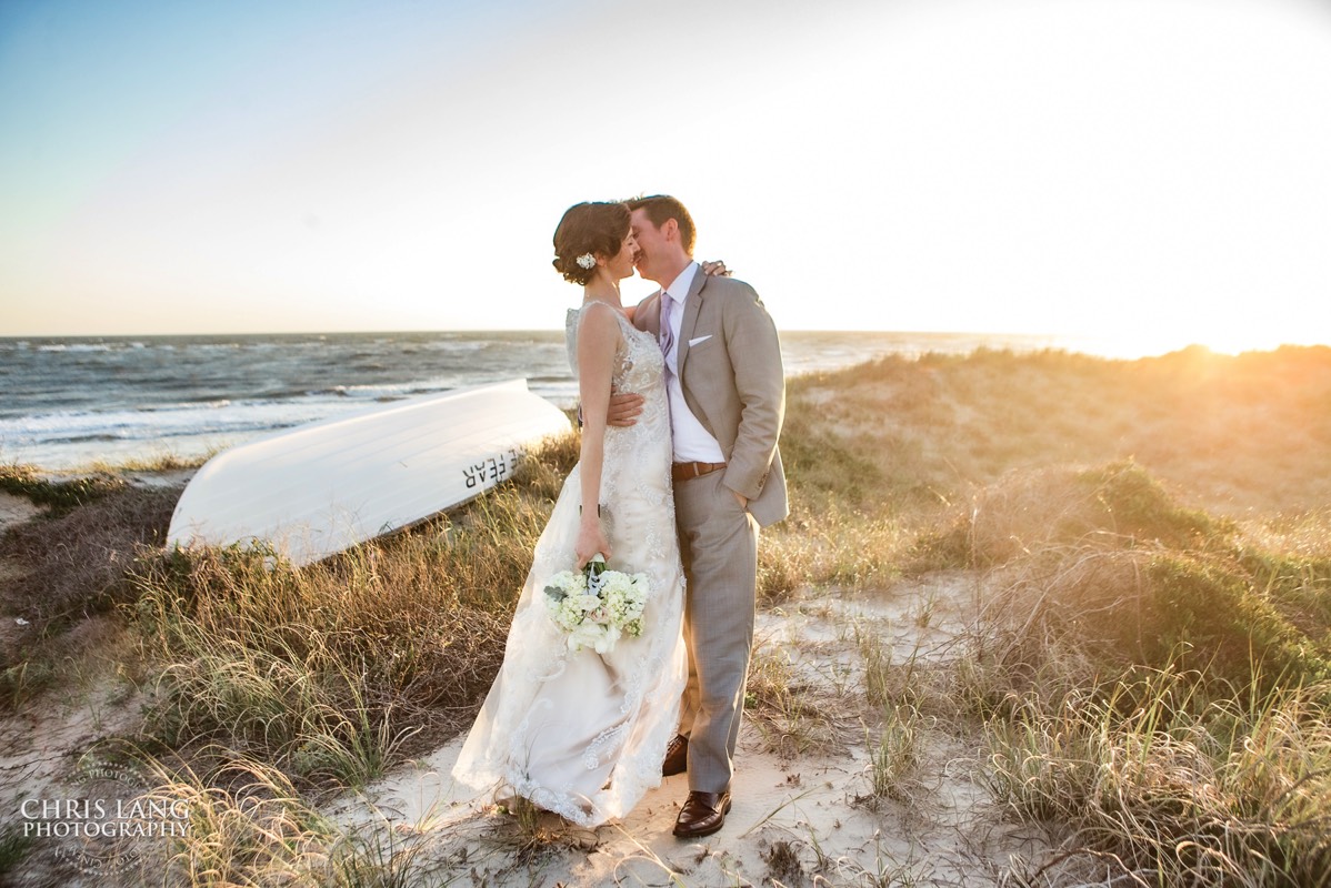 brode and groom embracing on the beach  in front  of the shoals club - Bald Head Island NC Weddings - Photographers - Bride - Groom - Wedding Dress - wedding photography - chris lang photography - destination wedding - Bald Head Island Wedding Venue 