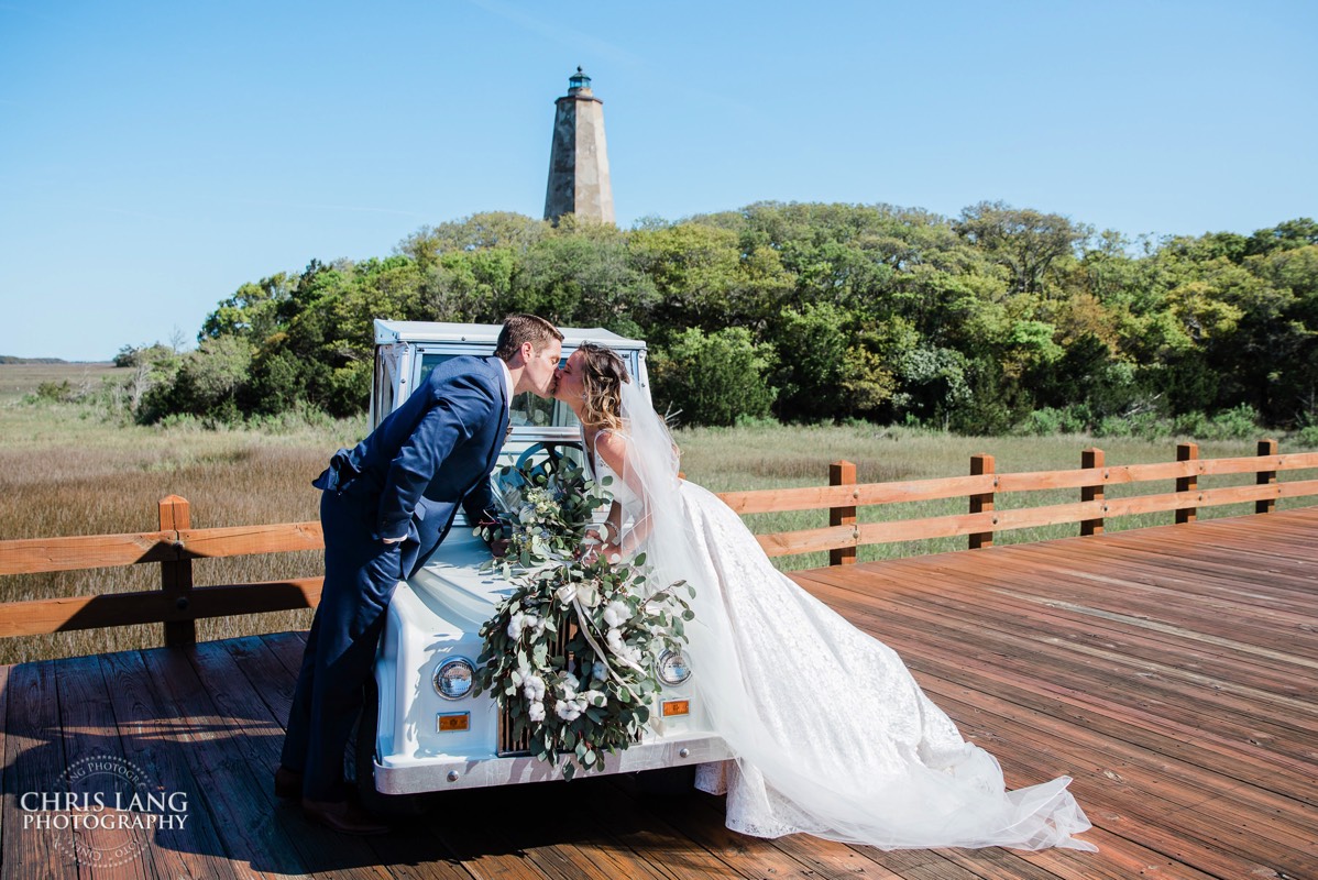 Bride and groom leaning over a golf cart kissing - Old Baldy Lighthouse  - Bald Head Island NC Wedding Photography - BHI Wedding Photographers - Wedding Dress -  Chris Lang Photography - Destination Weddings -  Bald Head Island wedding picture - BHI Weddings