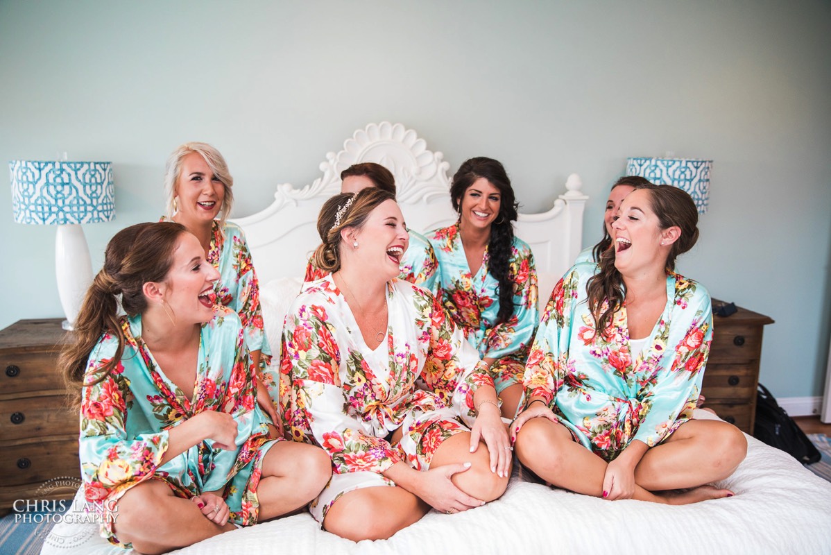 Bridesmaids in matching robes on bed laughing -- Bald Head Island NC Wedding Photographers - BHI Wedding Photography  - Bride - Groom - Wedding Dress -  - Chris Lang Photography - Destination Weddings -  Bald Head Island Wedding Venue 