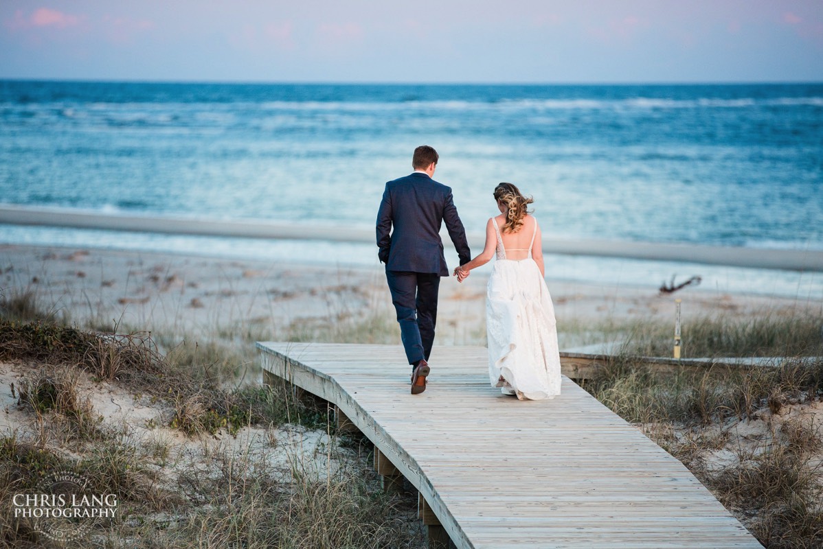 bride and groom walking down beach boardwalk - sunset - wedding photo idea - Wilmington NC Wedding Photographer - Wedding Photography - Wedding Photo - Chris Lang Photography